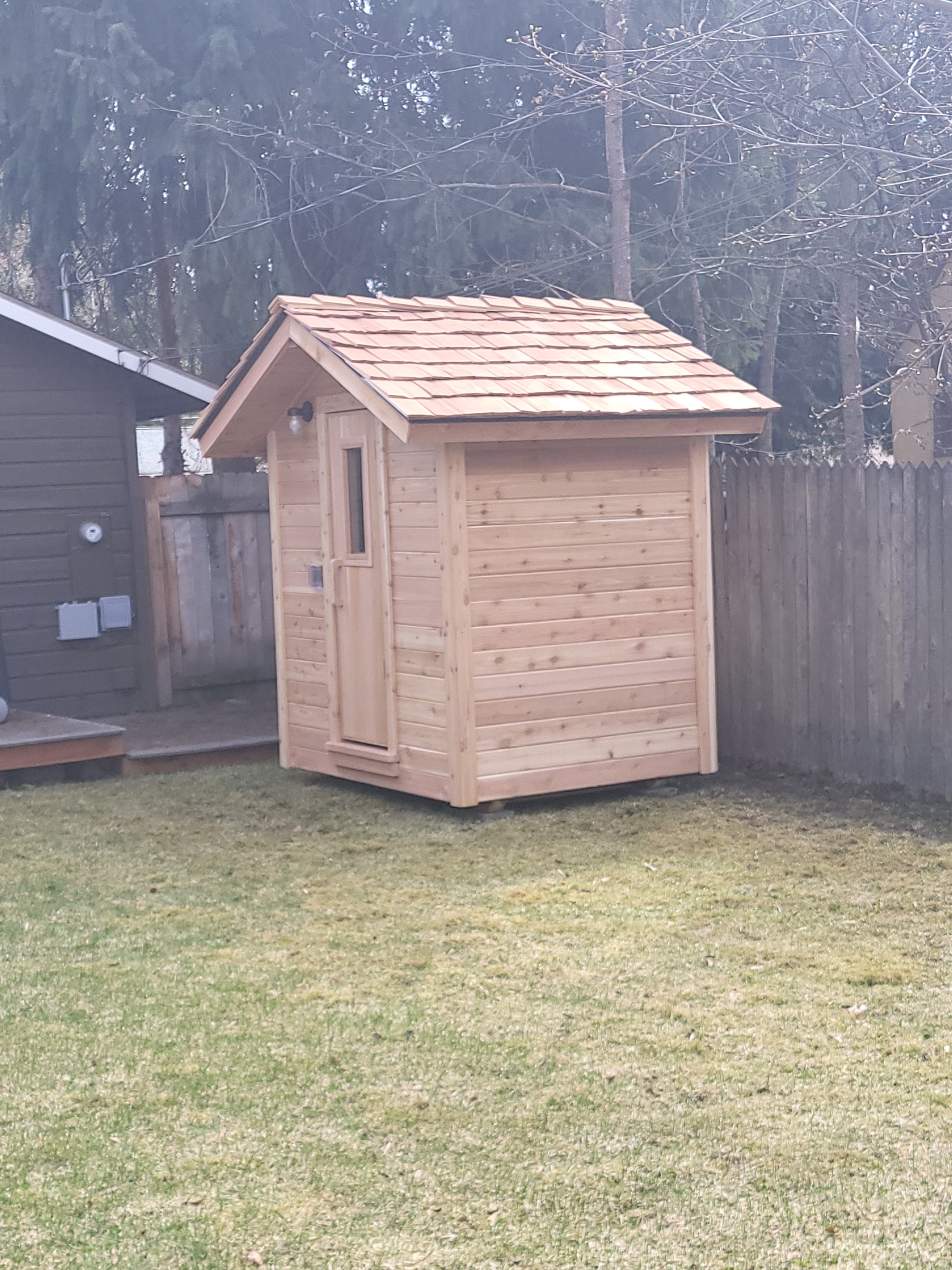 Custom build backyard modular plug and play sauna with cedar shake roof.